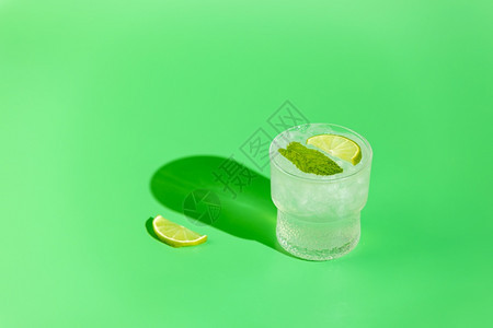假期社会的制造莫吉托新鲜的鸡尾酒包括石灰薄荷和玻璃中的冰在明日光下以绿色背景的水滴为绿底墨吉托清新饮料复制空间暑假和派对概念图片