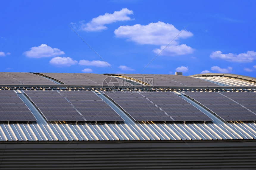 阳光仓库集电极工业建筑钢屋顶弯曲的太阳能板面以蓝色天空背景的白云为对比图片