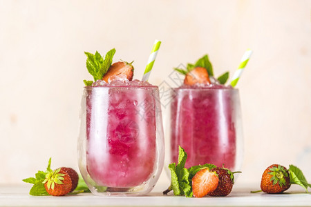 盛装草莓和冰块的新鲜夏季鸡尾酒在浅粉红背景上喝杯草莓苏打汽水玻璃目的液体图片