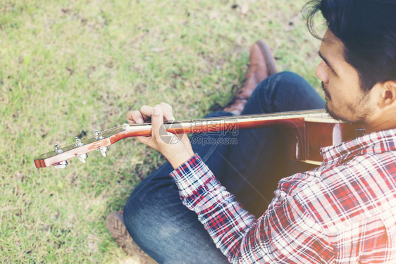 木板唱歌年轻的嬉皮士在公园里练习吉他快乐和享受p年轻的嬉皮士在公园里练习吉他快乐并喜欢弹吉他摇滚乐图片