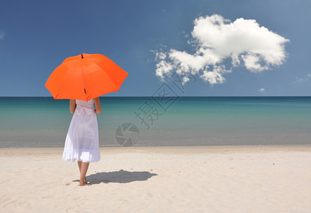 沙滩上撑着橙色雨伞的女孩图片