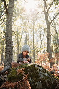 裤子之中小caucasians幼女的小孩蹲着穿羊毛帽在秋天的森林里蕨类植物图片