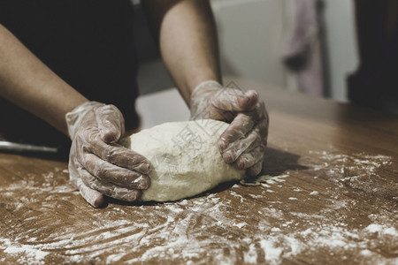 烹饪烘烤在土耳其妇女用塑料手套在桌子上做面团的手馅饼图片