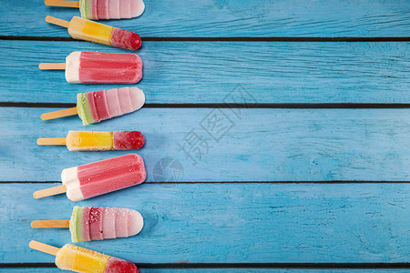 鲜花多彩的水果冰淇淋棒看起来新鲜可吃放在蓝色古老的木头上新鲜甜健康图片