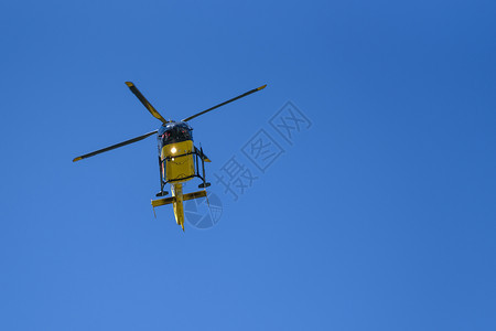 搜索安全速度用于在蓝天背景下开展消防和救援行动的一般黄色直升机低天使视线蓝色空背景图片