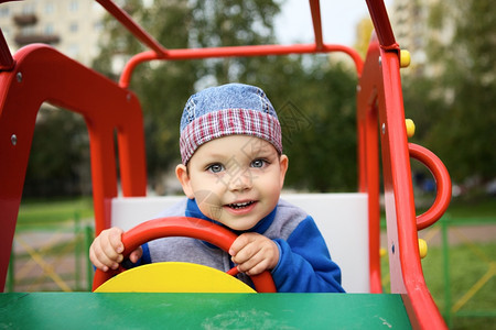 微笑丰富多彩的绿色小男孩在玩具车的游乐场耍图片