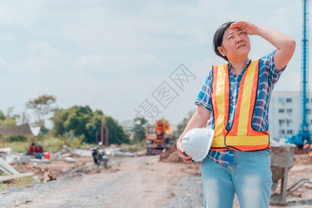 持白色安全头盔站在建筑工地前面的程妇女控制和检查建筑准确度概念组织Uniticstocontrolandcheckthebuil图片