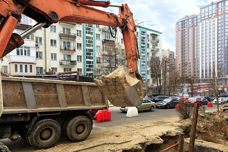 道路施工铺沥青一辆重型建筑挖土机的金属桶在修车道上理一名城市采集器时挖了一条战壕而个重型建筑挖掘机的金属桶在修车道上复一名城市采图片