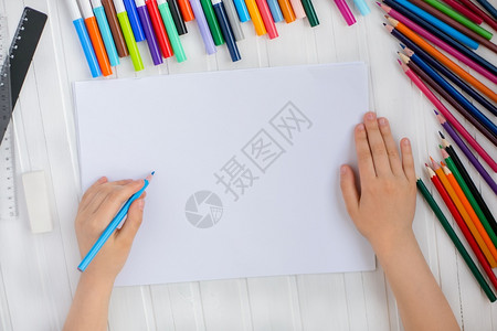 孩子颜色童手用彩铅笔涂在木制桌上一张白纸童子手用彩色铅笔画在纸上