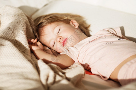 睡着的小女孩无忧虑的睡梦小宝床上有一个柔软玩具的小婴儿近身肖像一个美丽的睡童在编织的毯子上一种眼睛甜的图片