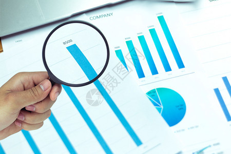 商人使用放大镜分析公司报价数据和图表中的统计数字并用放大镜来分析数据金融的经济玻璃图片