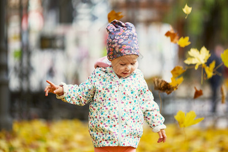 秋天在公园玩落叶的可爱小孩图片