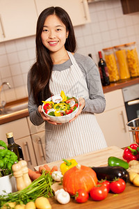 一顿饭绿色可口手拿着多彩色沙拉的亚洲笑脸女人站在厨房里图片