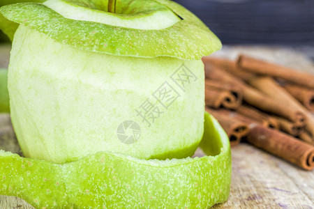 新鲜的剥开绿苹果与整个香味肉桂一起躺在黑木桌上关闭天然水果皮绿色苹调味颜图片