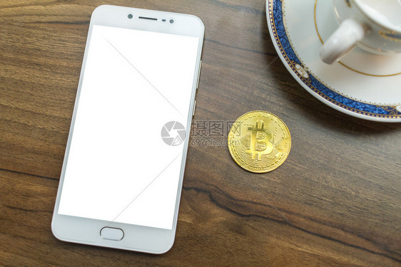 Bittcoin硬币和智能手机笔咖啡杯放在顶上旧木头办公桌钱包网络图片