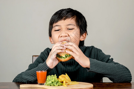 可爱的亚洲男孩吃一个美味的汉堡包幸福快乐青少年一顿饭男生图片
