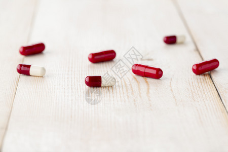 几种不同的可溶红白药物胶囊用于摄取明亮的木桌上特写镜头不同的红白药物胶囊用于摄取明亮的木桌上特写镜头痛复制一种图片