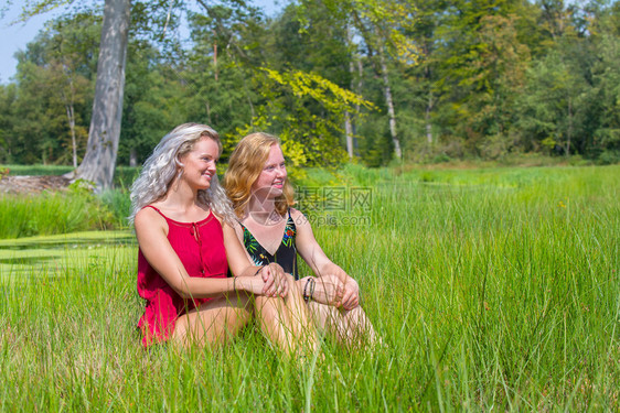 放松公园坐在自然草原上一起的金发和红头女人白种图片