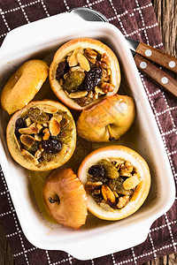 健康配有胡桃杏仁葡萄干苏丹豆黄油糖和肉桂传统秋冬甜点的新鲜烘烤苹果拍摄了选择焦点上方的图片焗填充图片