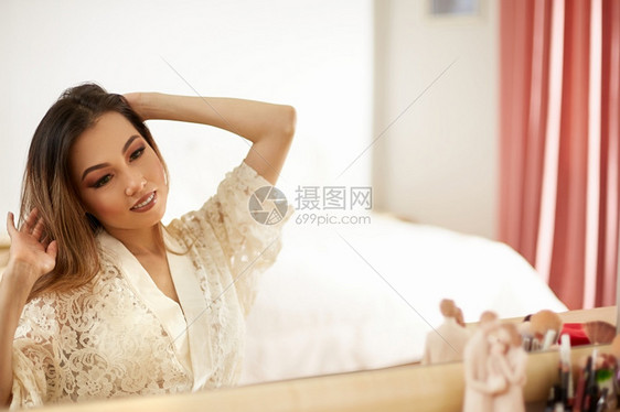 敷料一位年轻的亚洲美女穿着甲蕾丝装的服在清晨化妆和照镜子中浅的焦点有选择快乐化妆品图片