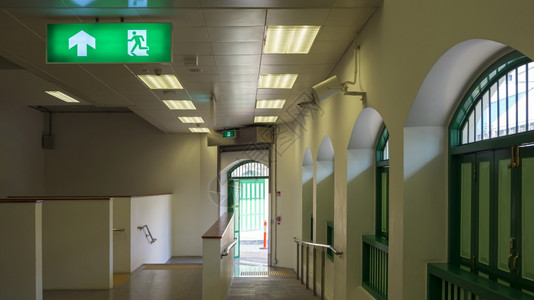 电的发光空中火车站走廊通道隧天顶上电动绿色紧急出口标志的绿色紧急出口箭图片