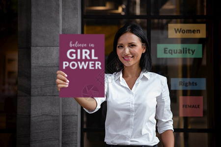 妇女平等促进男概念一位微笑的混合种族妇女在前面展示一个带有信息女权的委员会主义中间快乐的图片