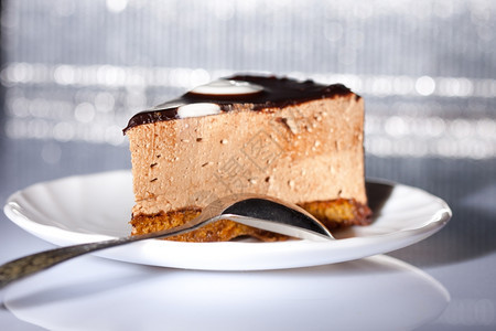 美味巧克力蛋糕餐桌上有勺子闪的银色背景奶油糕点糖图片