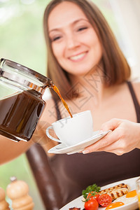 紧贴着面带微笑的黑发女人倒了一杯咖啡饮料可口请享用图片
