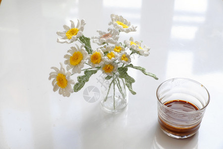 白桌上白色编织雏菊和咖啡杯图片