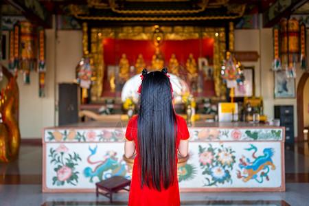 身着红色传统青山装饰的可爱亚洲年轻女子在泰国中华神庙为新年节举行布达雕像祷告仪式可爱的保持年轻图片