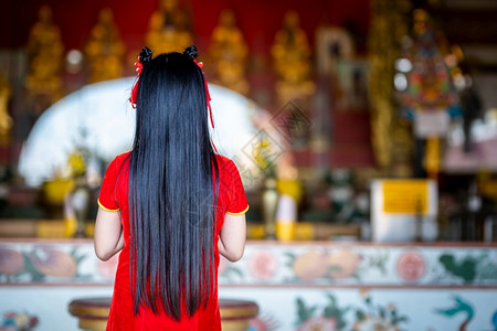 红色的女美丽身着红色传统青山装饰的可爱亚洲年轻女子在泰国中华神庙为新年节举行布达雕像祷告仪式图片