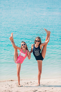 海岸热带滩上的小女孩一起玩耍快乐有趣的小女孩在热带海滩上玩得很开心俏皮图片