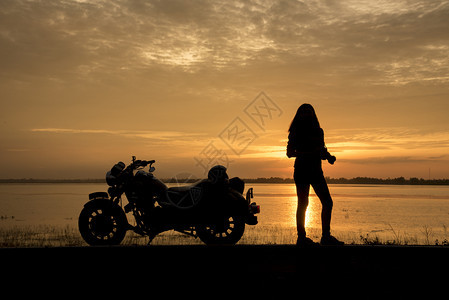 斩波器美丽的女子骑自行车享受日落女骑摩托车驾出世界旅行长途后放松自由生活方式旅行概念运输发动机图片