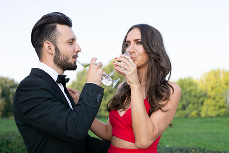 快乐的情侣与一杯酒或香槟站在户外玻璃人们优雅图片