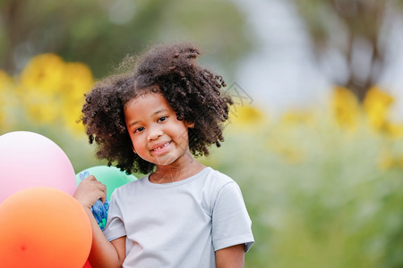 礼物一个黑卷发的女孩拿着彩色气球对摄影机微笑清白的卷曲图片