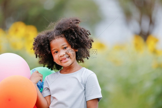 礼物一个黑卷发的女孩拿着彩色气球对摄影机微笑清白的卷曲图片