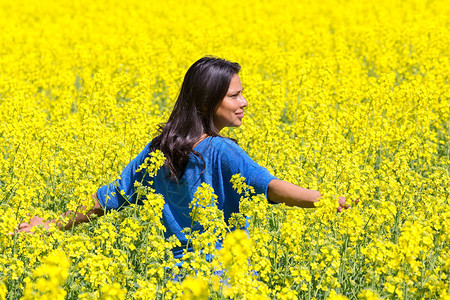 乐趣成人女站在盛开的黄色强暴种子田中年轻乡下女人站在鲜花之间繁荣的黄色强暴种子田中站立图片