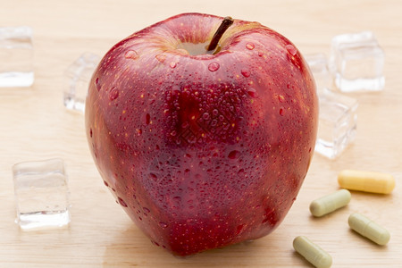 丰富多彩的医药胶囊红苹果富彩的药品胶囊和木本底的红苹果剂量寒冷的目图片