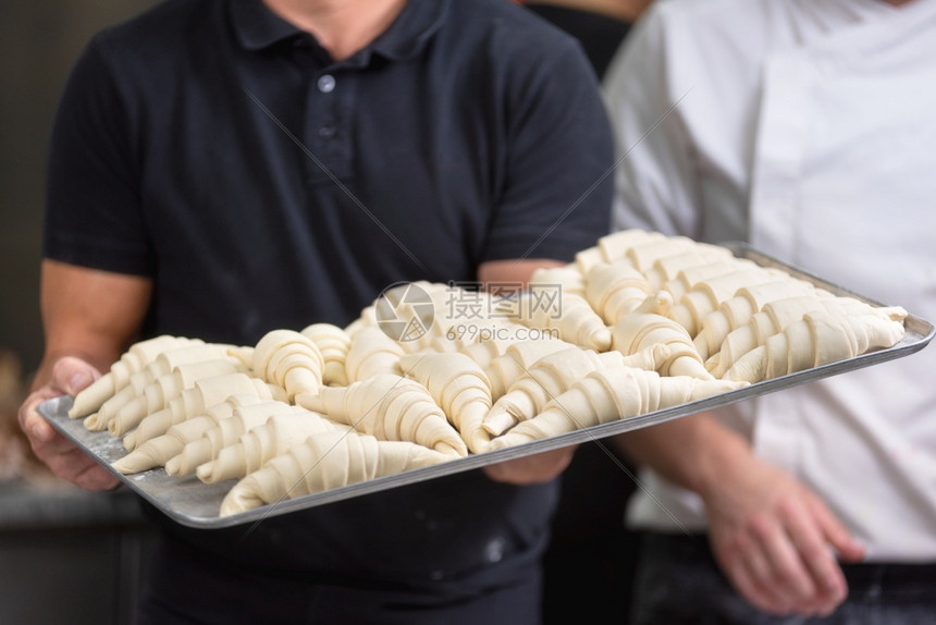 贴近糕点厨师显示一盘新鲜的生牛角面包屑贴近一个糕点厨师显示一盘新鲜的原羊角面包饼餐厅食物准备图片