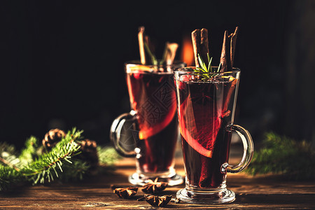 圣诞节日传统冬季饮酒在生锈的木制桌上装有玻璃杯中调味品的混合葡萄酒传统的酸果蔓为了图片