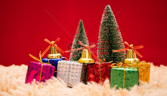 新的叮当火花圣诞节背景概念圣诞礼物盒和树有金铃松锥红底球和白的色图片