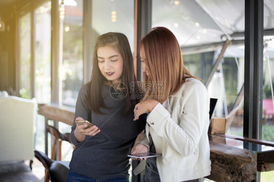 学生们会议年轻女孩在办公室客厅坐着时看朋友的电话感到兴奋和笑容感觉激动和微笑闲暇图片