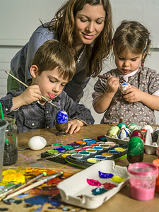 一位母亲和她的孩子为复活节画和装饰硬锅鸡蛋的照片煮熟坐着女士图片