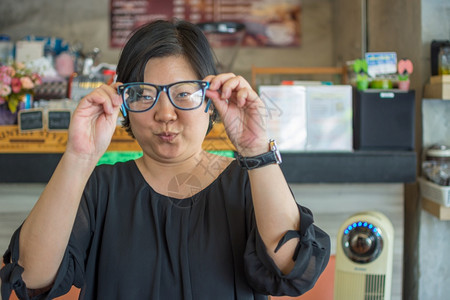 人们身着黑色裙子戴眼镜的四十多位亚洲妇女在咖啡店厅里有一个可爱的手势迷人泰国图片