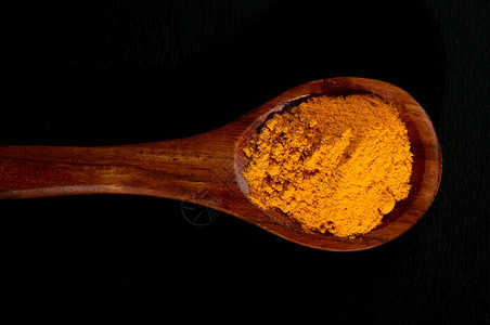 黑背景的勺子中突变粉调味料根姜黄图片
