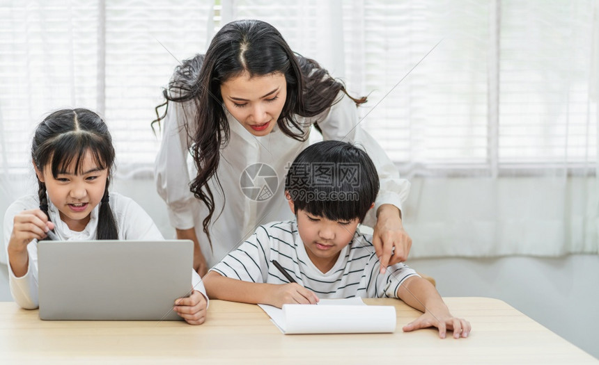 年轻亚洲单身母亲在家庭学校教育关系和家庭通信谈话概念中用电脑技术做家务工作或帮助女儿和子在家里教书或做务与庭有关的教育交流和对话图片