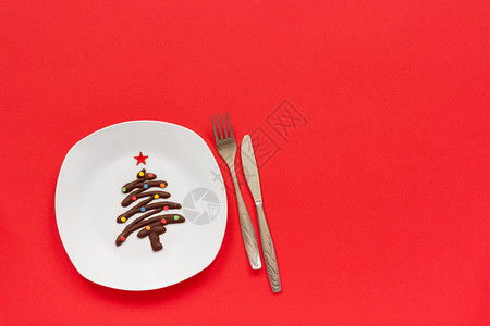 圣诞快乐树由巧克力制成白色盘子上涂满多的喷水红底餐具圣诞或新年情节在喜庆桌前讨论最佳观赏空间甜巧克力圣诞树在盘子和餐具上白色的象图片