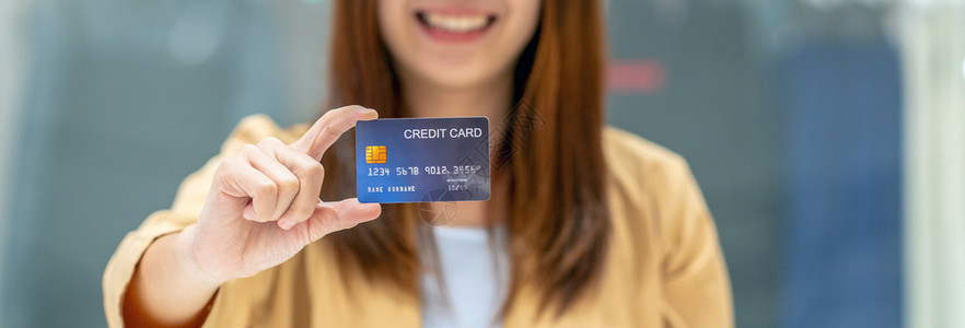 购买持有并展示信用卡供在服装店商的百货技术资金钱包和网上支付概念信用卡模型上在线购物的亚洲妇女银行家名单AbannerofAsi图片