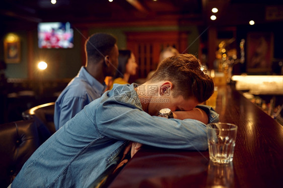搜集朋友喝啤酒男人在吧的柜台睡觉一群人在酒吧休息放松晚上生活方式友谊朋喝啤酒男人在吧的柜台睡觉夜店oopicapi图片