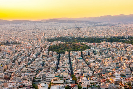 美丽的地标希腊雅典屋顶上的温暖夏日夜晚住宅楼和狭窄的街道鸟瞰雅典屋顶上的日落和金色天空中央图片